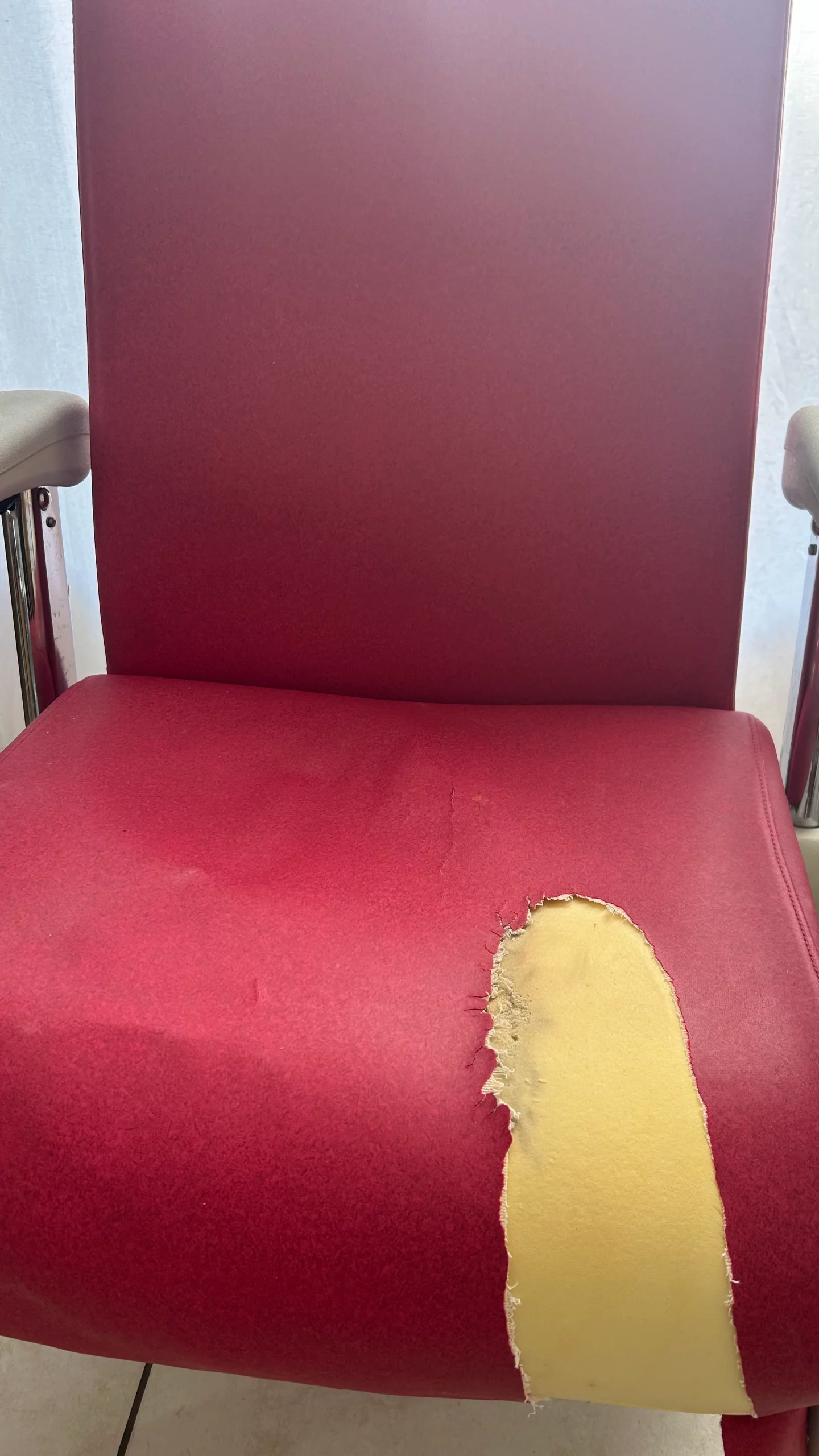 Fauteuil médical avant réfection, tissu déchiré et mousse apparente.